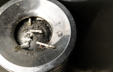 cigarette butts and black background in metal ashtray