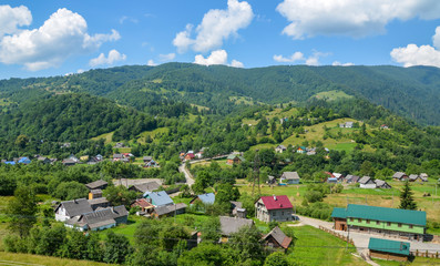 Fototapeta premium Landscape of the Carpathian village Kvasy against the background of green trees and mountains, Transcarpathia, Ukraine