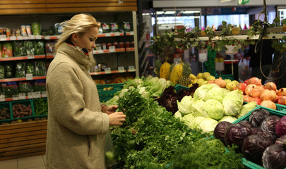 young housewife chooses vegetables in vegetable shop at the supermarket