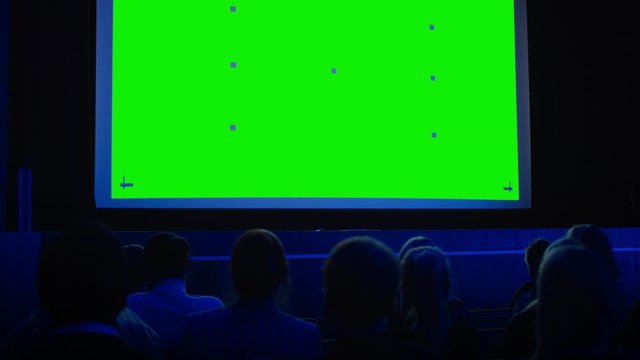 In the Modern Movie Theater Captivated Audience Watching New Blockbuster Film on Mock-up Green Screen. People Watching Video Game Tournament Streaming, Live Concert Video, New Product Release Trailer