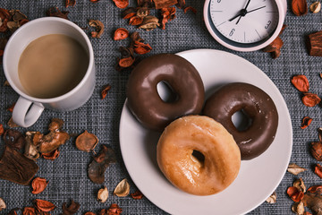 Breakfast in the morning with coffee, donut and a clock giving the hour.