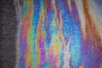 Spilled fuel. A beautiful multi-colored spot. Gasoline stains on the surface. Bright acid colors. Abstract texture. All colors in one fuel spot. Gasoline crisis.