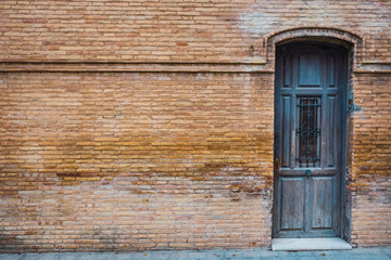 Old wooden door in a red brick wall as background for text.