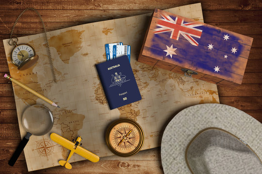 Top view of traveling gadgets, vintage map, magnify glass, hat and airplane model on the wood table background. On center, official passport of Australia and your flag.