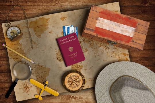 Top view of traveling gadgets, vintage map, magnify glass, hat and airplane model on the wood table background. On center, official passport of Austria and your flag.