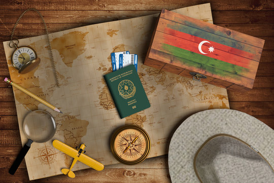 Top view of traveling gadgets, vintage map, magnify glass, hat and airplane model on the wood table background. On center, official passport of Azerbaijan and your flag.