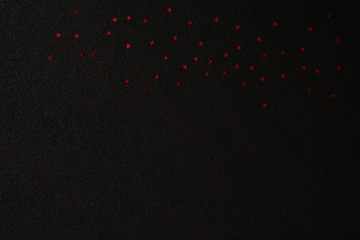 Red shiny stars on crepe paper with diagonal markings and a space for text. Black diagonal pattern for your creativity. Black pattern with shiny red stars.