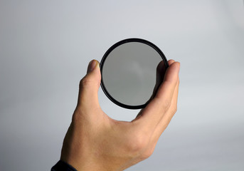 Hand holds ND lens camera filter on white background