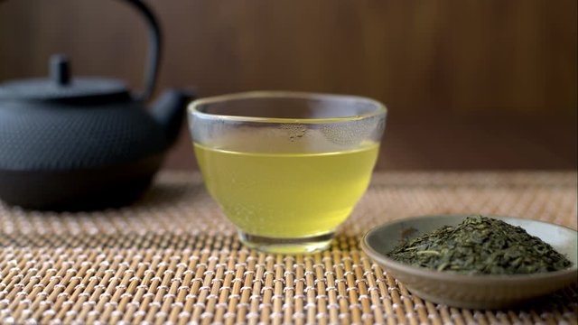 Hot Japanese green tea in glass cup with teapot and leaf