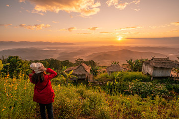 Back view of tourist woman traveling and looking to beautiful sunrise view of the mountains range...