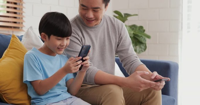 Little boy using smartphone at home. Father looking little boy play game in smartphone with attractive smile.