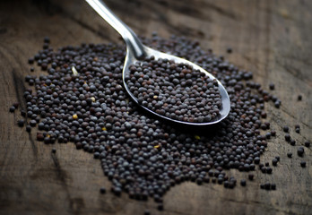 Black mustard seeds on a wooden table