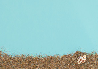 Sea shell and sand on blue background. Summer time, summer holiday vacation concept. Greeting or invitation card. Flat lay, top view style with copy space for your text.