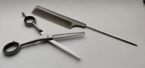 Scissors and comb on a warm white background