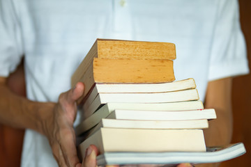Men holding a stack of paperback books