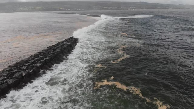 powerful waves hitting hilo bay breakwall in winter low fast aerial