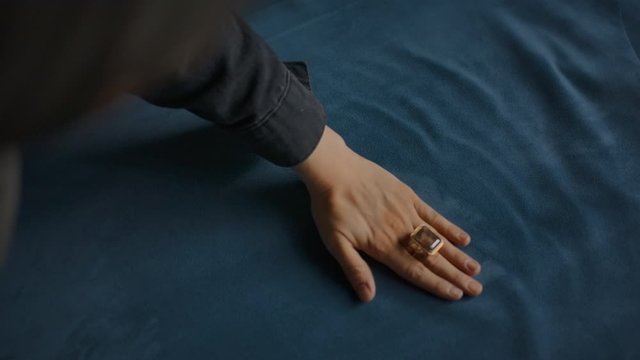 Smoothing silk velvet textile with brush and elegant woman hand. Flattening piles of fabric. Touching plush and soft material. Fabric unique texture. Designing and tailoring clothes