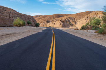 Landscape of road leading through desert area with barren stone hills at Mecca Wilderness in Southern California