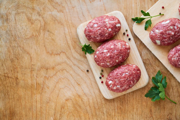 Raw minced meat cutlets on a wooden cutting board