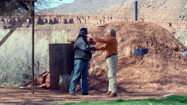 Native American Men Greet Each Other in Front of Hogan