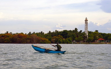 Fisherman on Batticaloa Lagoon with a colonial-era lighthouse in the background