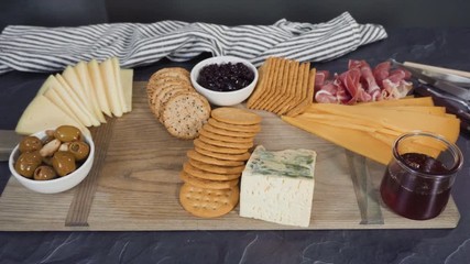 Arranging gourmet cheese, crakers, and fruits on a board for a large cheese board.