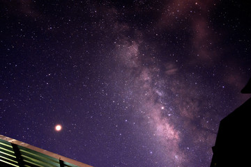 Milky way glaxy and stars with house roof top. Long exposure photograph with grain.
