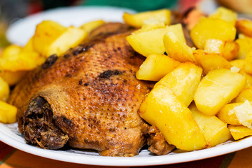 oven-baked golden-crusted duck with potatoes lies on the dish