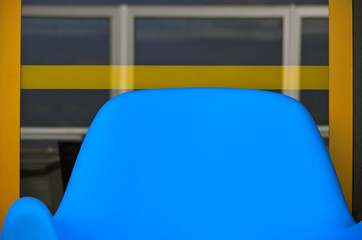 Blue backrest of plastic chair against Glas with reflection on outside deck of cruiseship or cruise...