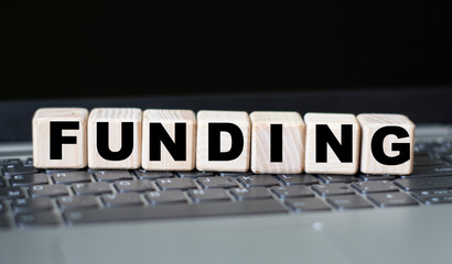 concept word funding on cubes on the background of a laptop