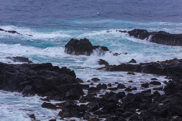 Beautiful Nature scene of sea wave hitting on the black stone shoreline at Jeju Island, South Korea.