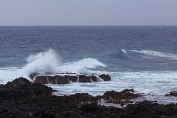 Beautiful Nature scene of sea wave hitting on the black stone shoreline at Jeju Island, South Korea.
