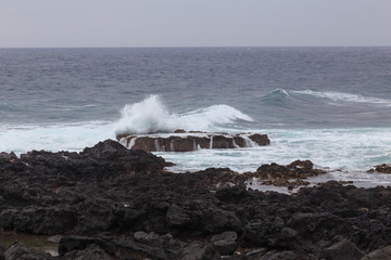 Fototapeta na wymiar Beautiful Nature scene of sea wave hitting on the black stone shoreline at Jeju Island, South Korea.