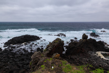 Beautiful Nature scene of sea wave hitting on the black stone shoreline at Jeju Island, South Korea.