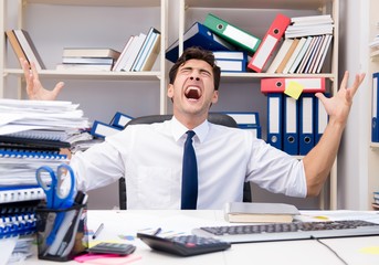 Businessman working in the office with piles of books and papers