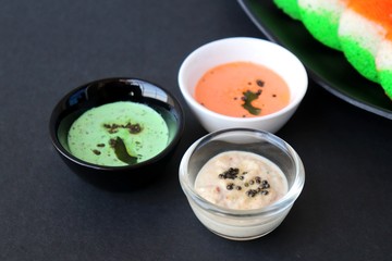 Tiranga Idli or Tricolor Idly cooked in  Indian National Flag colors - saffron or orange, white and green. Served with tiranga chutney. Concept for Indian Independence or Republic day greeting card.