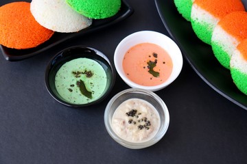 Tiranga Idli or Tricolor Idly cooked in  Indian National Flag colors - saffron or orange, white and green. Served with tiranga chutney. Concept for Indian Independence or Republic day greeting card.