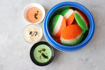 Tiranga Idli or Tricolor Idly cooked in  Indian National Flag colors - saffron or orange, white and green. Served with tiranga chutney. Concept for Indian Independence or Republic day greeting card.