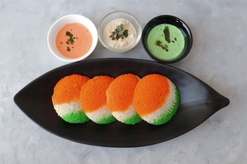 Tiranga Idli or Tricolor Idly cooked in  Indian National Flag colors - saffron or orange, white and green. Served with tiranga chutney. Concept for Indian Independence or Republic day greeting card.