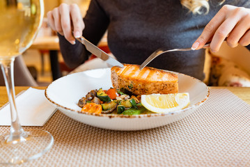 woman eating salmon steak with roasted vegetables
