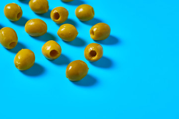 Scattered many pickled olives on blue table on kitchen. Space for text
