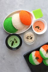 Tiranga Idli or Tricolor Idly cooked in  Indian National Flag colors - saffron or orange, white and green. Served with tiranga chutney. Concept for Indian Independence or Republic day greeting card.