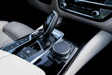 Track control buttons near automatic gear stick in a white leather interior of a modern car. Car interior details. Car inside.