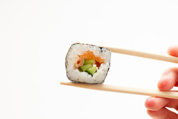 Woman hand holding fresh sushi roll with wooden chopsticks on white background