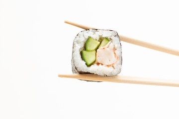 hand holding fresh sushi roll with wooden chopsticks on white background
