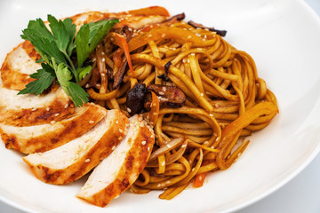 Pan asian food. Wok noodles on a white plate, close up
