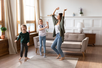 Overjoyed mum have fun dance with little kids at home