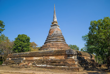 Fototapeta premium Ancient stupa of the Buddhist temple Wat Chedi Ngarm on a sunny day. The surroundings of Sukhothai. Thailand