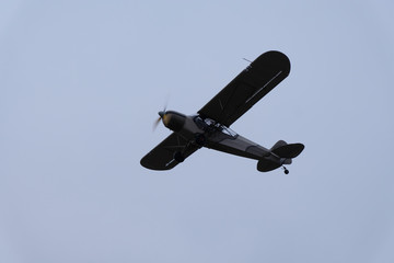 A small airplane is flying in the cloudy sky.