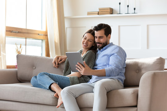 Happy couple relax on couch using tablet together